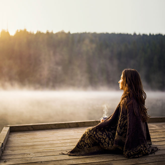 Femme se relaxant avec et café au lever du soleil.